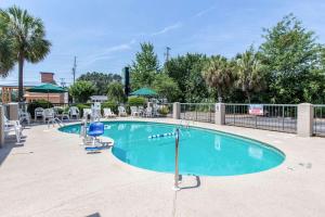 une grande piscine avec des chaises et des parasols dans l'établissement Quality Inn, à Cordele