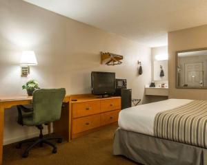 a hotel room with a bed and a desk with a television at Econo Lodge Inn & Suites at Fort Moore in Columbus