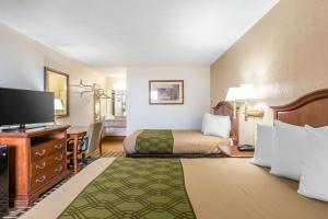 a hotel room with a bed and a flat screen tv at Econo Lodge Midtown in Savannah