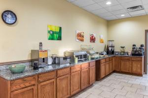 a kitchen with wooden cabinets and a clock on the wall at Quality Inn & Suites Conference Center Thomasville in Thomasville