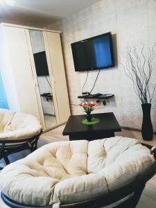 a living room with a white couch and a tv at Apartment on Chapaeva in Borisov