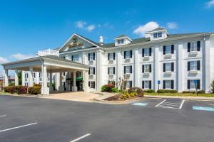 a white hotel with a parking lot in front of it at Quality Inn Rome South in Rome