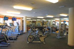 un gimnasio con filas de cintas de correr y máquinas elípticas en Clarion Suites Roatan at Pineapple Villas, en First Bight