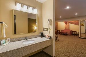 a bathroom with a sink and a mirror and a living room at Quality Inn Waverly in Waverly