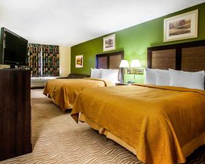 a hotel room with two beds and a flat screen tv at Quality Inn & Suites in Champaign