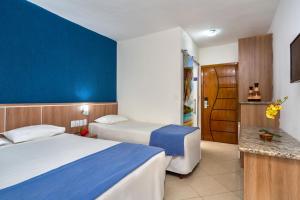 a hotel room with two beds and a blue wall at Hotel Beach Hills in Porto Seguro