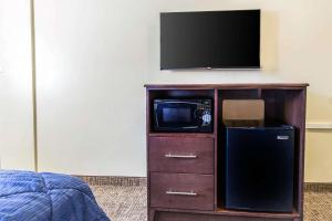 a tv on top of a cabinet with a microwave at Rodeway Inn Lyons - La Grange in Lyons