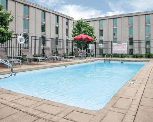 una piscina con sillas y una sombrilla frente a un edificio en Comfort Inn Bloomington near University, en Bloomington