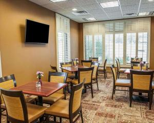 un restaurante con mesas y sillas y TV de pantalla plana en Comfort Inn Bloomington near University, en Bloomington