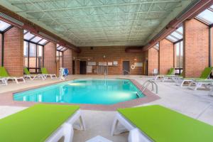 uma grande piscina com mesas verdes e cadeiras em Comfort Inn & Suites Evansville Airport em Evansville