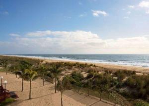 einen Sandstrand mit Palmen und dem Meer in der Unterkunft Quality Inn Oceanfront in Ocean City