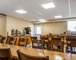 a dining room with tables and chairs and a kitchen at Quality Inn & Suites in South Portland