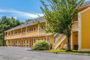 a large yellow building with a tree in front of it at Econo Lodge Freeport - Brunswick Area in Freeport