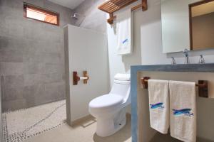 a bathroom with a toilet and a shower with towels at Punta Zicatela Hotel in Puerto Escondido