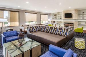 a living room with a brown couch and blue chairs at Comfort Inn College Park North in Beltsville