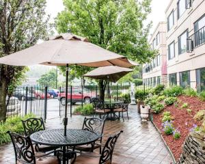 un patio con mesas, sillas y una sombrilla en Quality Inn Southfield, en Southfield