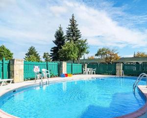 a large swimming pool with chairs and a fence at Rodeway Inn Madison Heights in Madison Heights