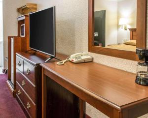 a hotel room with a desk with a phone and a mirror at Rodeway Inn Madison Heights - Detroit in Madison Heights