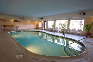 una gran piscina en un hotel con mesas y sillas en Comfort Suites Grand Rapids North en Comstock Park