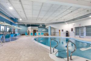 uma piscina num quarto grande com cadeiras e mesas em Comfort Inn Bay City - Riverfront em Bay City