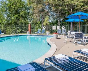a swimming pool with chairs and an umbrella at Quality Inn Auburn Hills in Auburn Hills