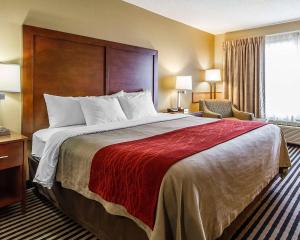 a hotel room with a large bed with a red blanket at Comfort Inn Owatonna near Medical Center in Owatonna