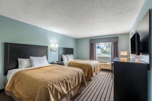 a hotel room with two beds and a flat screen tv at Rodeway Inn in Ludington