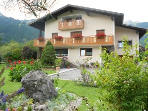 a house with a balcony and flowers in the yard at Ferienwohnung Schreieck Maria in Hofen
