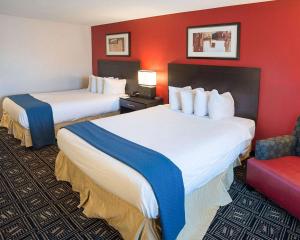 um quarto de hotel com duas camas e uma parede vermelha em Quality Inn em Brooklyn Center