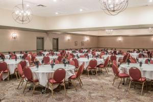 a banquet hall with white tables and red chairs at enVision Hotel Saint Paul South in South Saint Paul