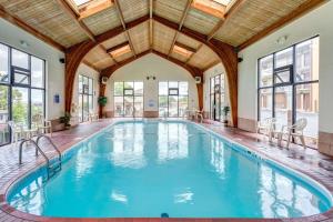 an indoor pool with a wooden ceiling and windows at Quality Inn West in Branson