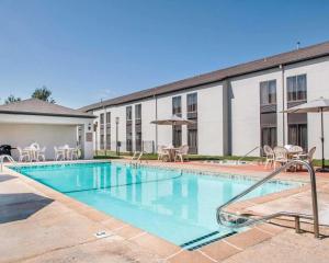 a swimming pool with tables and chairs and a building at Greenstay Inn & Suites Court View in Springfield