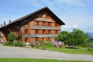 una grande casa in legno con una recinzione di fronte ad essa di Bauernhof Schneider a Egg
