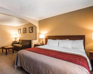 a hotel room with a large bed and a chair at Quality Inn & Suites Bethany in Bethany