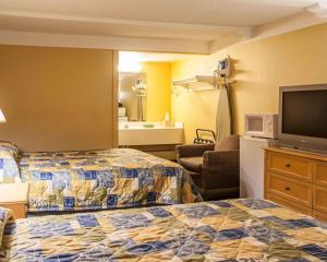 a hotel room with two beds and a flat screen tv at Relax Inn Saint Charles in St. Charles
