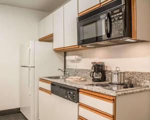 a kitchen with a white refrigerator and a microwave at Suburban Studios Columbia - Hwy 63 & I-70 in Columbia