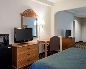 Habitación de hotel con cama, TV y escritorio. en Quality Inn Magee, en Magee
