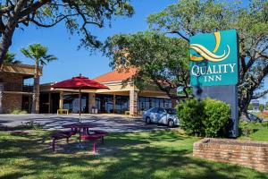 una señal para una posada de calidad con una mesa de picnic en Quality Inn Biloxi Beach, en Biloxi