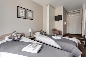 sypialnia z 2 łóżkami, krzesłem i telewizorem w obiekcie All Dreams Rooms w Petersburgu