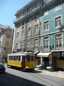 a yellow tram on a street in front of a building at Pensão Prata in Lisbon