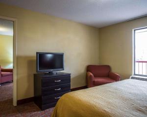a hotel room with a bed and a tv and chairs at Quality Inn & Suites Monroe in Monroe