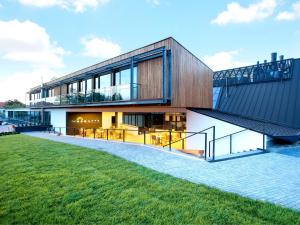 a modern house with a glass facade and a lawn at Regatta Hotel Restauracja Spa in Poznań