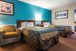 a hotel room with two beds and a chair at Econo Lodge Elizabeth City in Elizabeth City