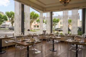 a restaurant with tables and chairs and large windows at The Originals City, Hôtel Napoléon, La Roche-sur-Yon (Inter-Hotel) in La Roche-sur-Yon