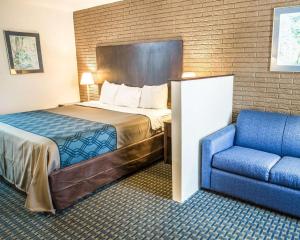 Pokój hotelowy z łóżkiem i niebieskim krzesłem w obiekcie Rodeway Inn & Suites Wilmington North w mieście Wilmington