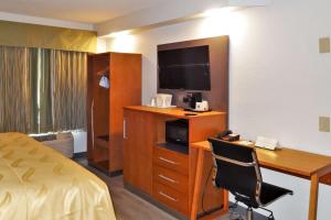 a hotel room with a bed and a desk with a television at Quality Inn & Suites Raleigh North in Raleigh