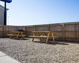 two picnic tables in front of a wooden fence at Comfort Inn in Jamestown