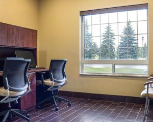 a desk with a computer and a chair in front of a window at Comfort Suites Minot in Minot