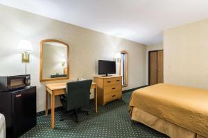 a hotel room with a bed and a desk with a computer at Quality Inn Columbia Mall in Grand Forks