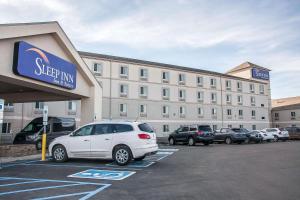 ein großes Gebäude mit Autos auf einem Parkplatz in der Unterkunft Sleep Inn & Suites Conference Center and Water Park in Minot
